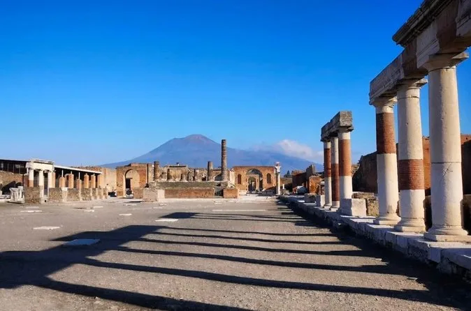 The Forum of Pompeii with columns on the right and Vesuvius on the horizon under a deep blue sky