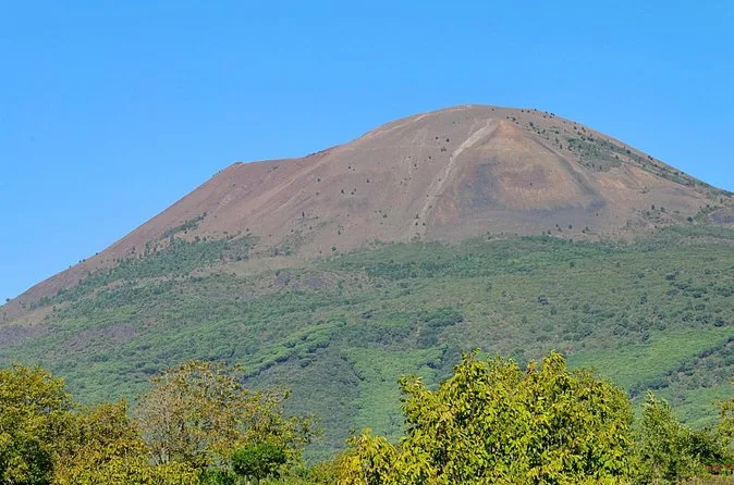 The green lower slopes and brown cone of Vesuvius under a blue sky